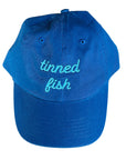 Blue hat with TINNED FISH embroidered in light blue on front.