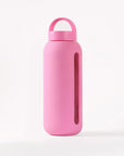 Glass water bottle with a protective silicone sleeve and screw on cap in pink.