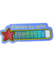 A sticker that reads "Fueled by spite" with a red star and glitter scale.