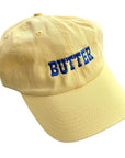 Yellow hat with BUTTER embroidered on front in blue.