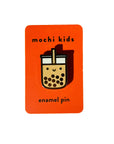 An orange rectangular card with the text 'mochi kids enamel pin' and an enamel pin of a bubble tea cup and straw.