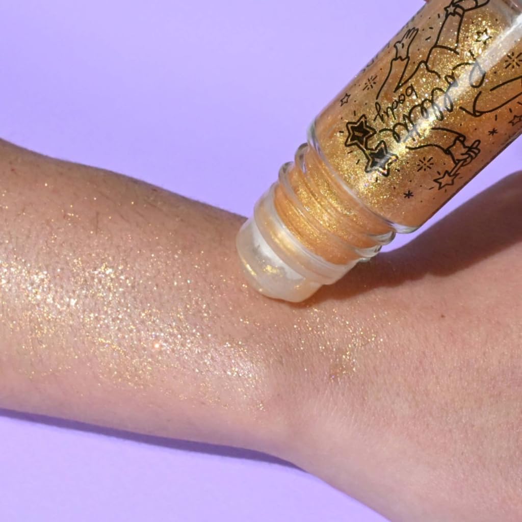 Roll-on bottle of glittery gold cream being applied to a wrist against a purple background