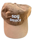 Brown ballcap with 'SOY SAUCE' text on a textured white surface
