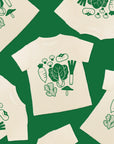 Green background with six shirts in arranged at random. The tee is white with green screen print of popular asian vegetables.