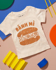 White tee screen printed with brown ink text BANH MI above a smiling banh mi sandwich.