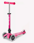 A pink and white three wheeled push scooter with the front two wheels lit up with LED lights.