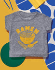 Grey tee screen printed with yellow ink text RAMEN above a smiling bowl of ramen with chopsticks, and soup spoon.