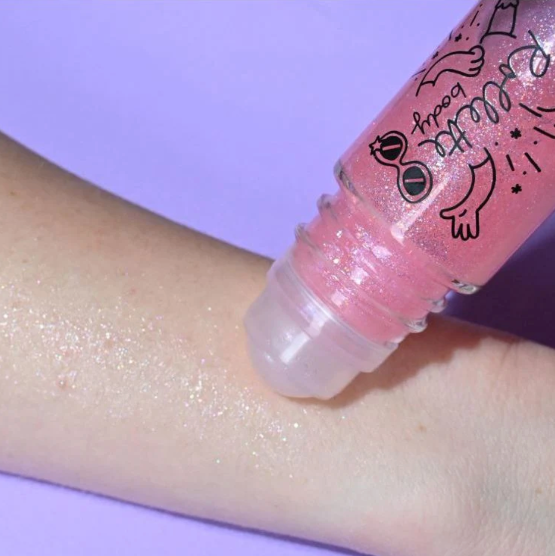 Pink roll-on body glitter being tested on someone's forearm.