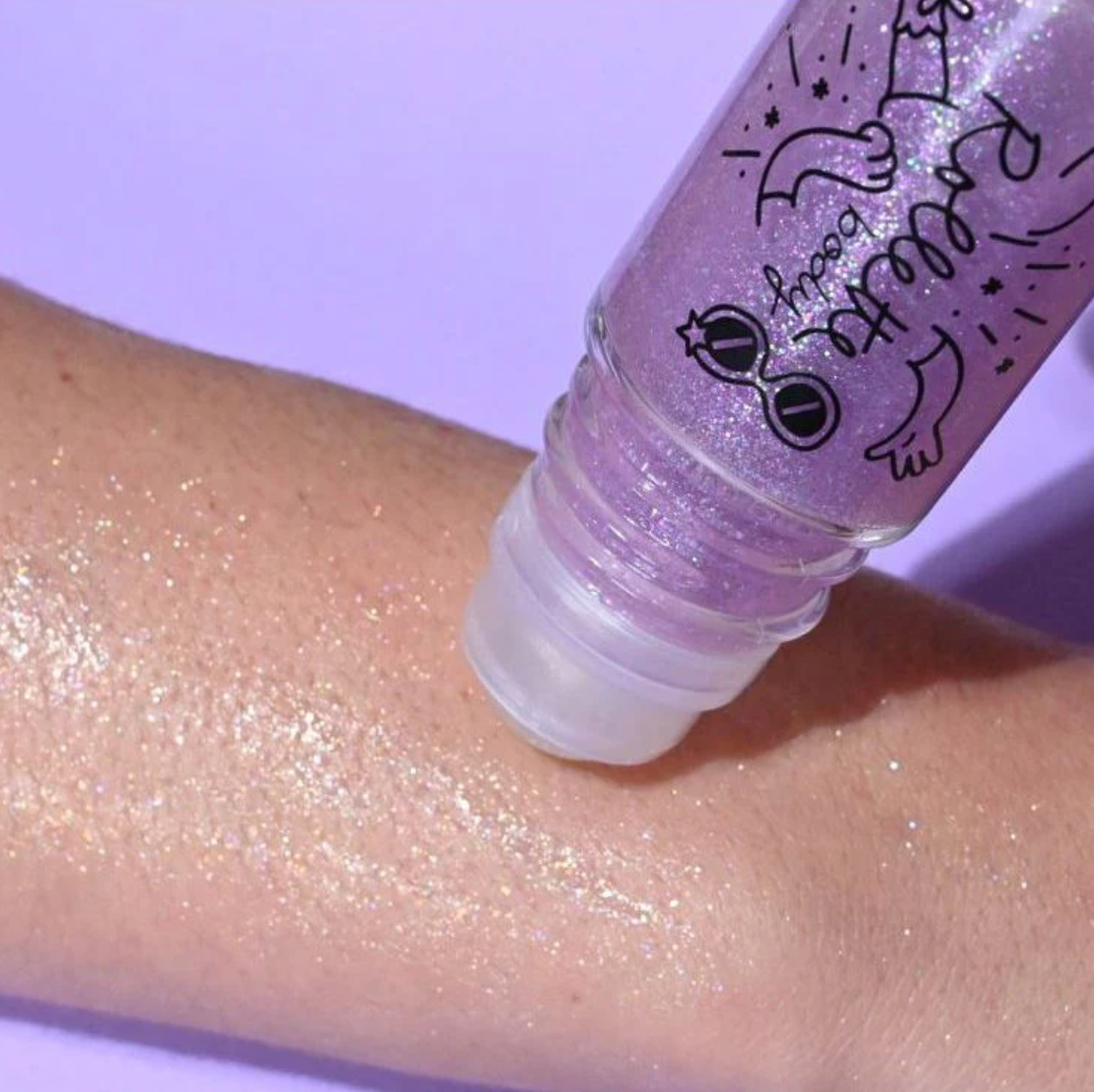 Purple roll-on body glitter being demonstrated on someone's forearm.