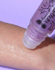 Purple roll-on body glitter being demonstrated on someone's forearm.