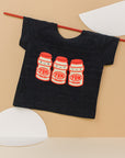 Black tee screen printed with three red and yellow yakult yogurt bottles with smiley faces.
