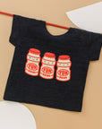 Black tee screen printed with three red and yellow yakult yogurt bottles with smiley faces.
