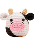 Crocheted cow toy with a pink nose on an orange background