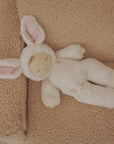 A baby doll with closed eyes wearing a white bunny costume.