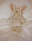 A baby doll with closed eyes wearing a white bunny costume.