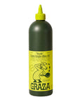 Dark green bottle of Graza "Sizzle" Extra Virgin Olive Oil with bright yellow label, featuring a cartoon cook drizzling oil into a pan, conveying culinary delight.