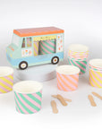 A colorful pastel ice cream truck box with 12 ice cream cups and spoons inside surrounded by more ice cream cups and spoons.