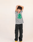A child modeling a grey tee screen printed with a green Christmas tree with red ornaments, black happy face and MERRY MERRY adorning the tree.