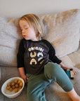 A sleeping child modeling a gray baseball tee with black sleeves printed with white text ONIGIRI above four smiling onigiri.
