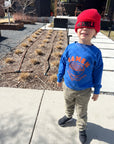 A child modeling a blue sweatshirt screen printed with orange ink text RAMEN above a bowl of ramen with a smiley face, chopsticks, and soup spoon.