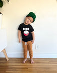 A child modeling a black tee screen printed with white ink text RICE above a red smiling bowl full of white rice.