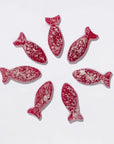 Seven blackberry sour fish gummies arranged in a circle.