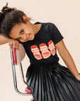 A child modeling a black tee screen printed with three red and yellow yakult yogurt bottles with smiley faces.