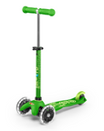 A Green and light Green three wheeled push scooter with the front two wheels lit up with LED lights.