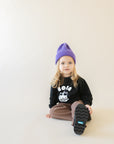 A child modeling a black sweatshirt with screen printed white ink text BOBA above a smiling glass of boba.