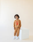 A child modeling brown sweatshirt screen printed with red ink, text KIMCHI and cabbage and jar of kimchi, both smiling.
