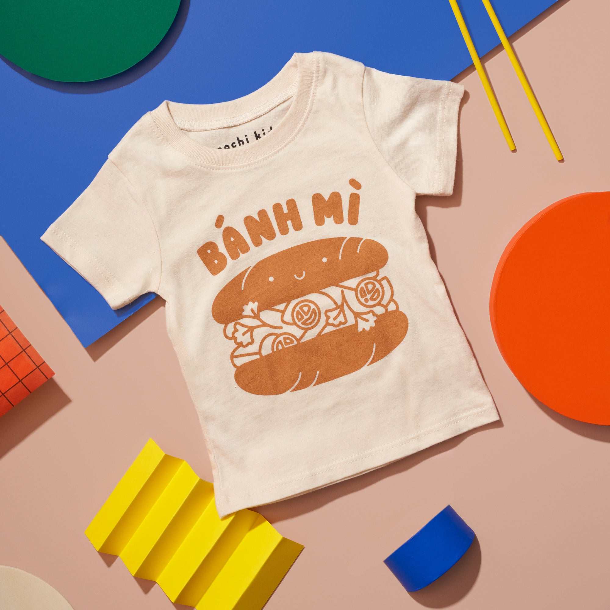White tee screen printed with brown ink text BANH MI above a smiling banh mi sandwich.