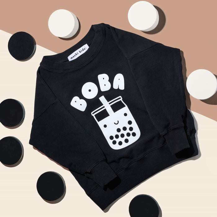 Black sweatshirt with screen printed white ink text BOBA above a smiling glass of boba.