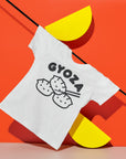 White tee with screen printed black ink text GYOZA above three smiling dumplings.