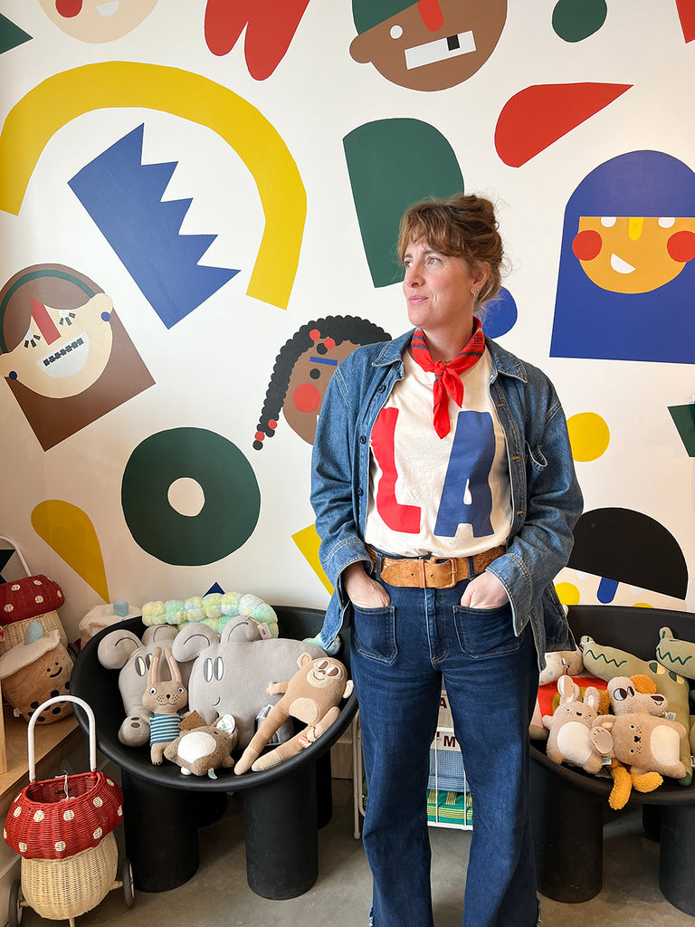 Woman wearing red white and blue LA tee against a colorful background.