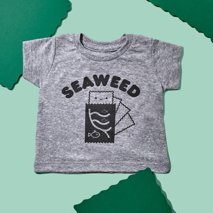Grey tee screen printed with black text reading: "SEAWEED" above a smiling package of seaweed with fish on the front.
