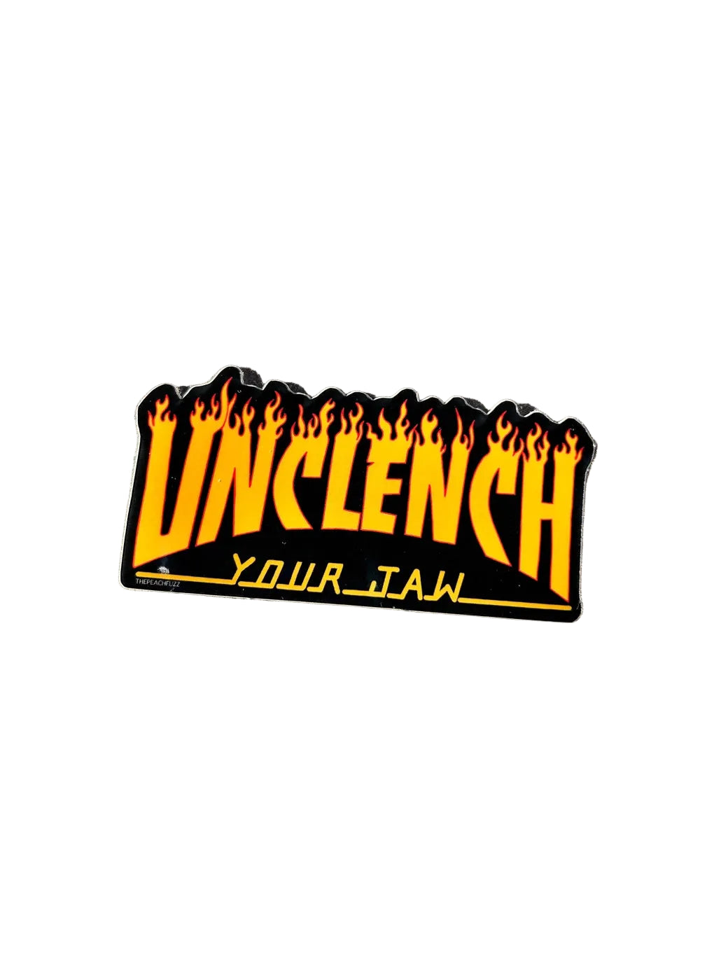Sticker with 'Unclench Your Jaw' text on a metallic surface