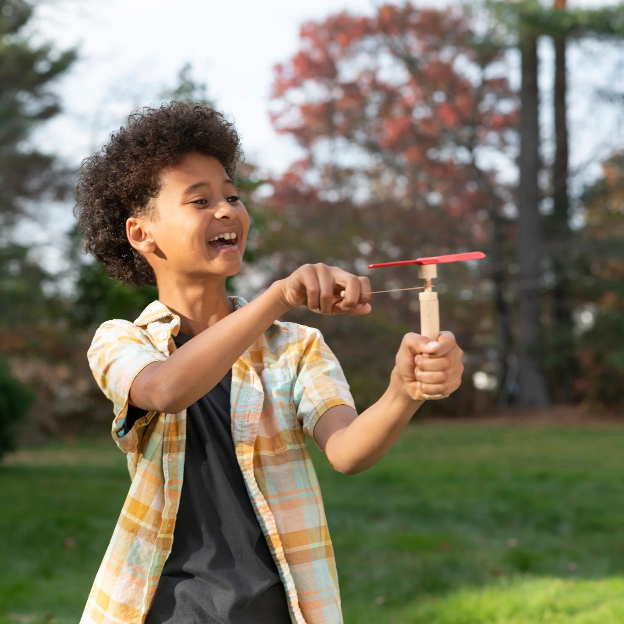 A child pulling the wind up string on a hand helicopter.