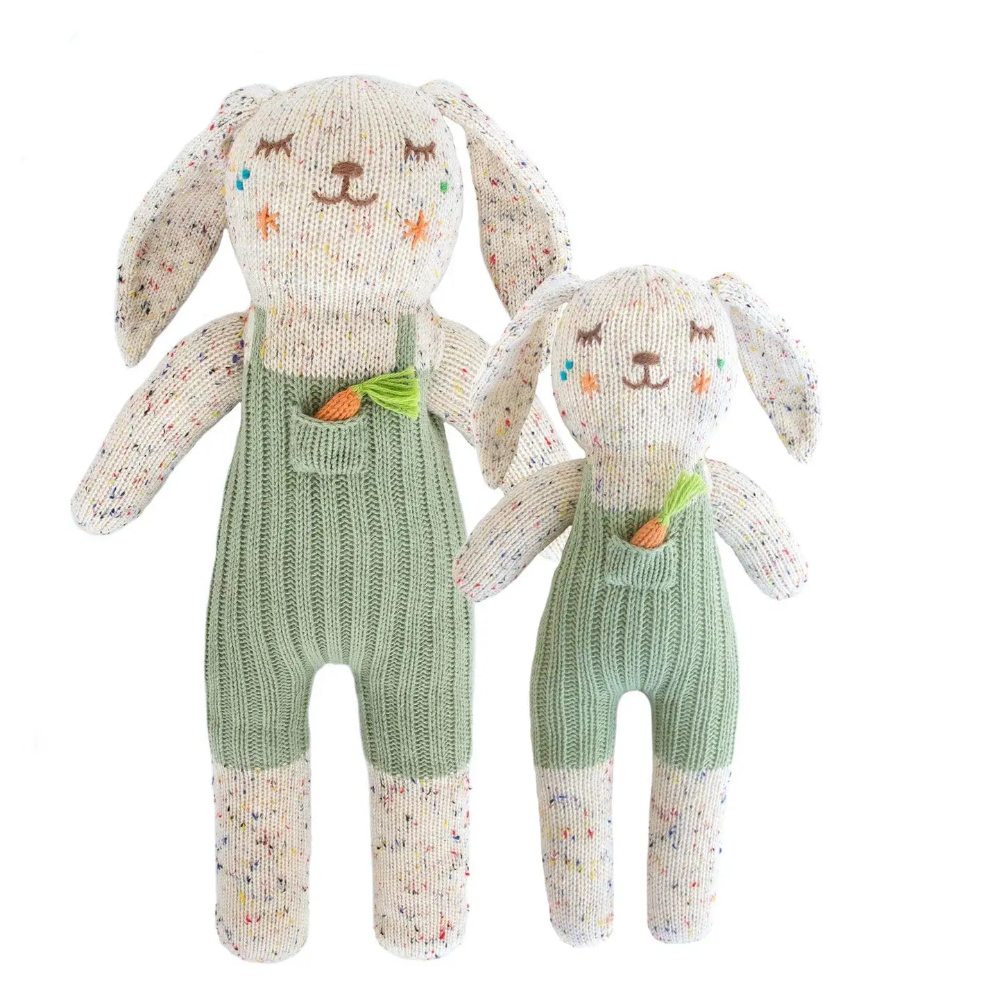 Two knitted bunny toys with green overalls on a white background