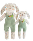 Two knitted bunny toys with green overalls on a white background