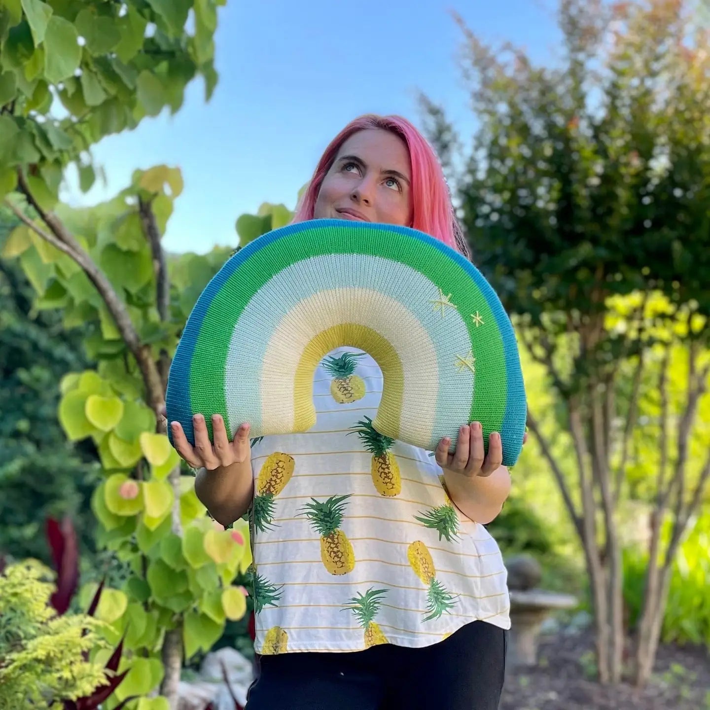 Person holding a colorful woven hat with pineapple design outdoors