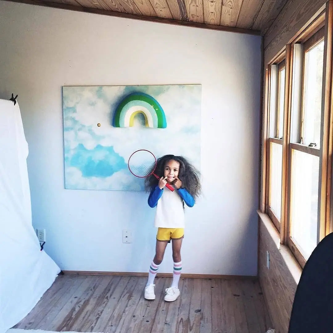 Child standing in a room with a colorful abstract painting on the wall