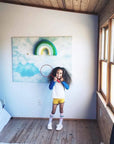 Child standing in a room with a colorful abstract painting on the wall