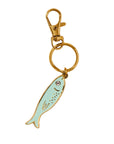 Sardine-shaped keychain with gold clasp on a beige background