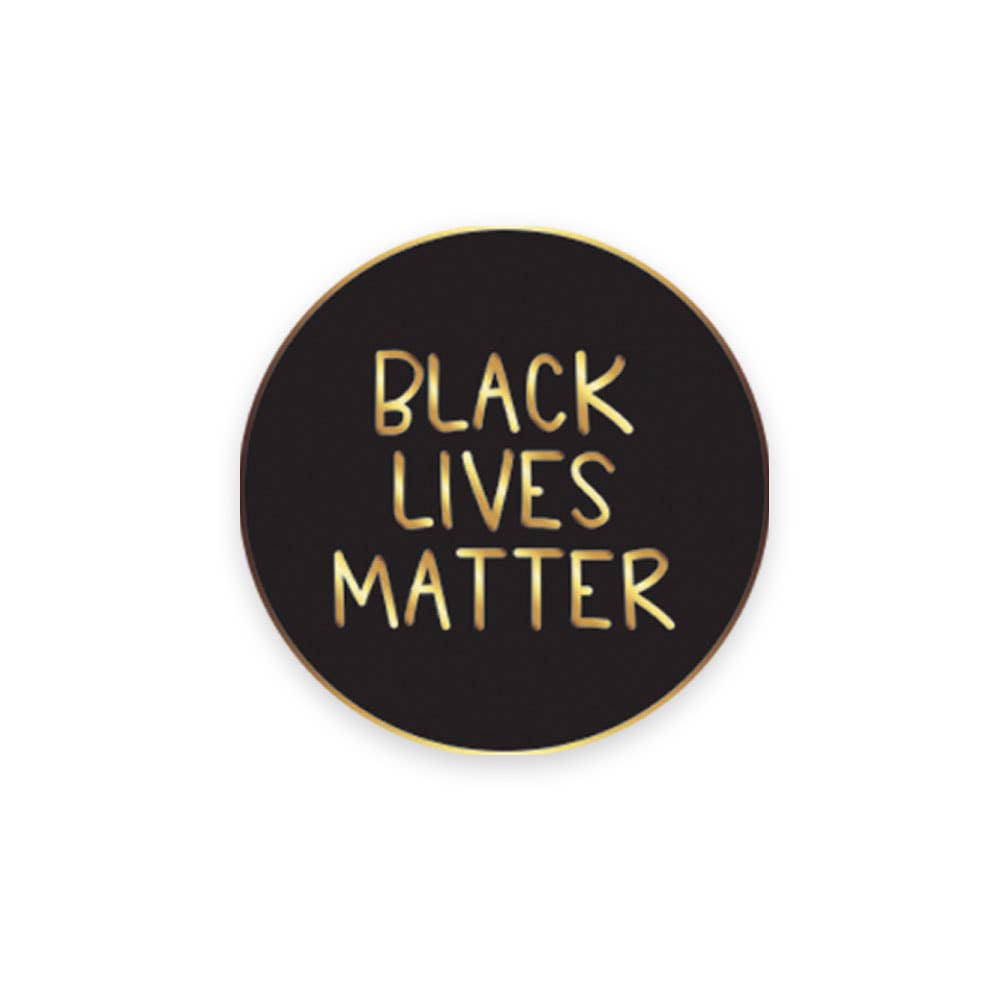 A circular black enamel pin with the text 'BLACK LIVES MATTER' in gold lettering, with a gold plating and a butterfly clasp on the back.